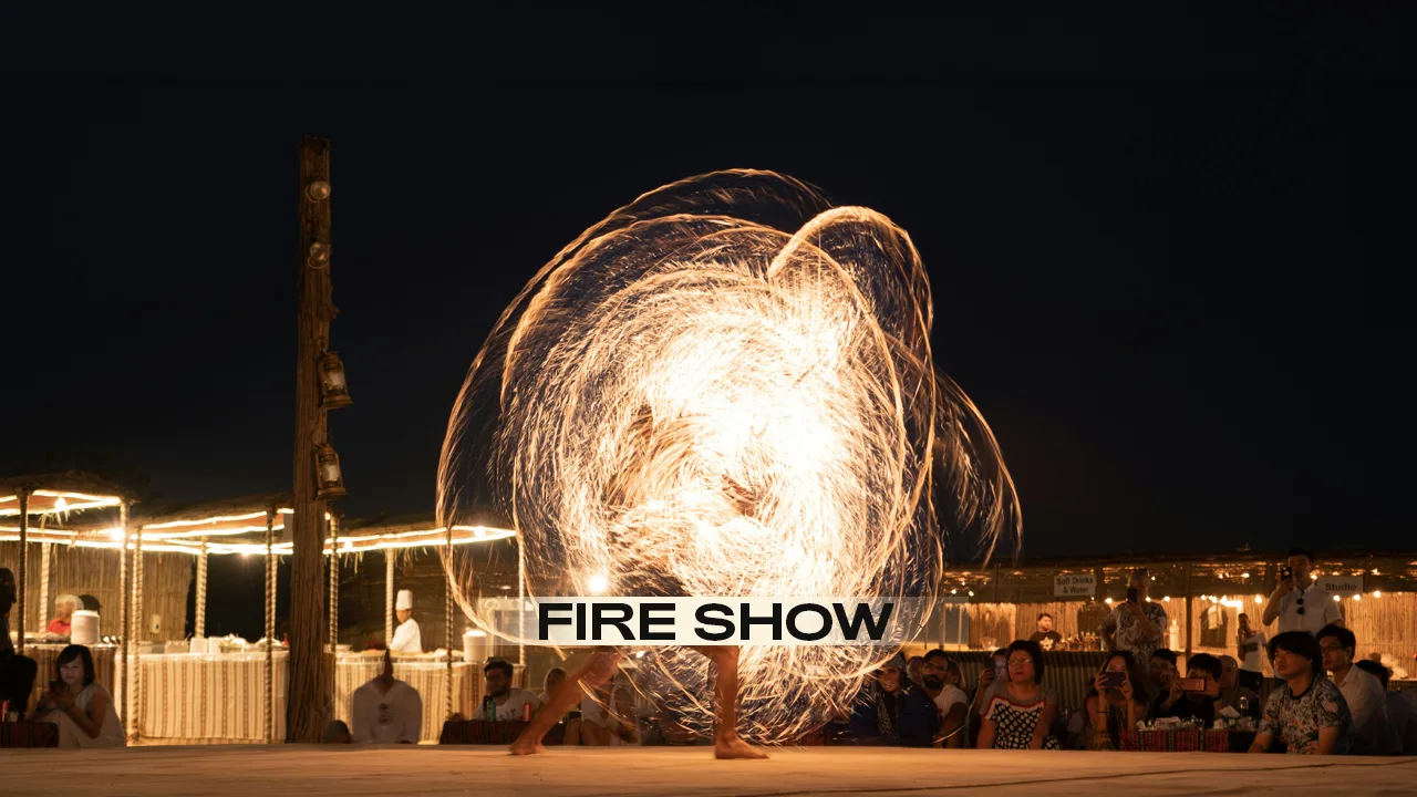 Professional fire dancer performing fire breathing show during evening desert safari in Dubai Arabian desert camp