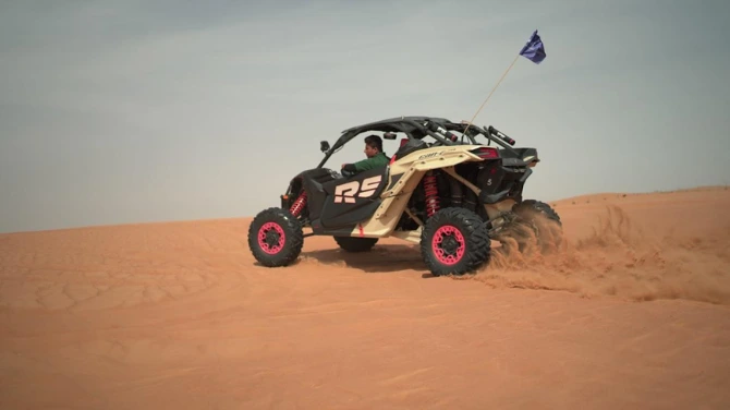 Polaris RZR dune buggy driving on Dubai desert dunes during an off-road adventure tour